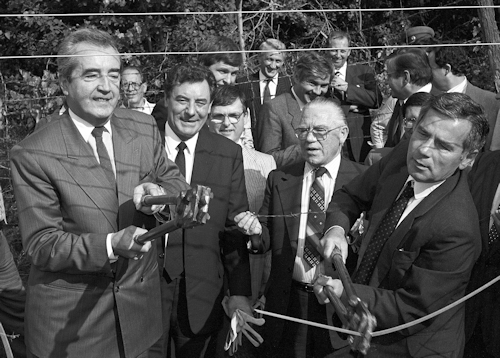 Politicians cutting through a wire fence