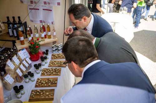 Important people examining a food booth at a market
