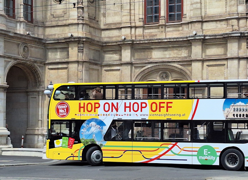 A sightseeing bus in front of an opera house