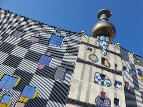 Façade of the Spittelau incinerator in the sun with the golden ball tower behind