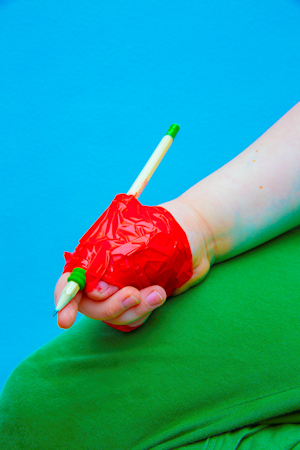 Child's hand with a pen taped to it