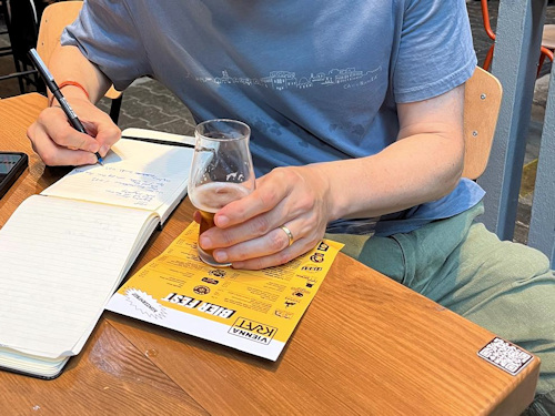 Man taking notes while holding a glass of beer