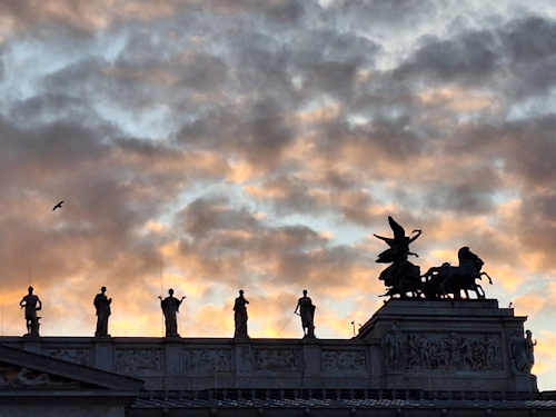 Roof statues silhouetted against a sunset sky