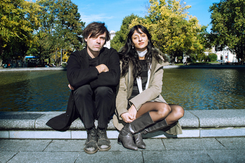 Two people sitting in front of a small lake