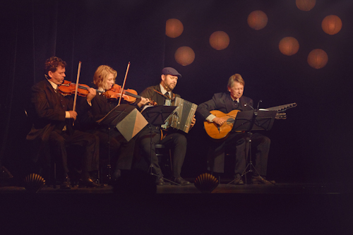 Four people playing string instruments and an accordian