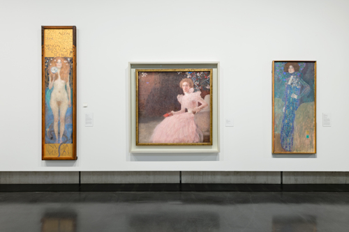 Three Klimt paintings on a gallery wall
