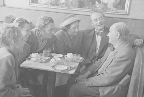 Post-war group at a café table enjoying a laugh