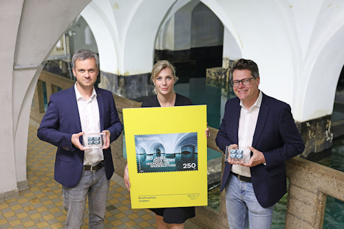 Three people holding a giant stamp