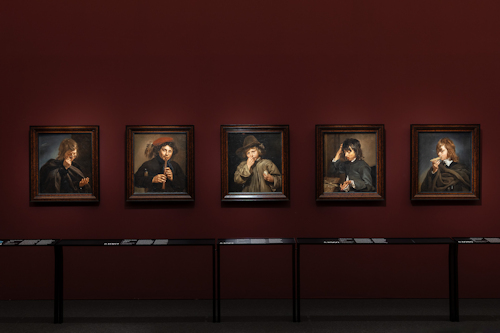 View of paintings hung along a wall in an art museum